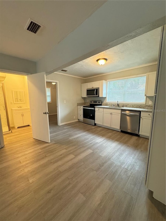 kitchen with white cabinets, ornamental molding, visible vents, and stainless steel appliances