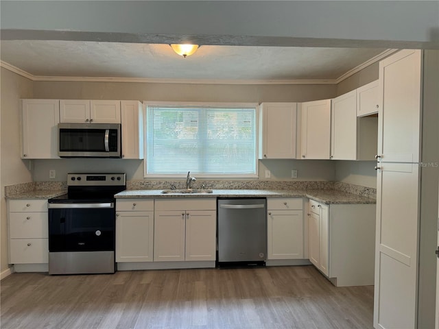 kitchen featuring white cabinets, crown molding, light wood-type flooring, stainless steel appliances, and sink