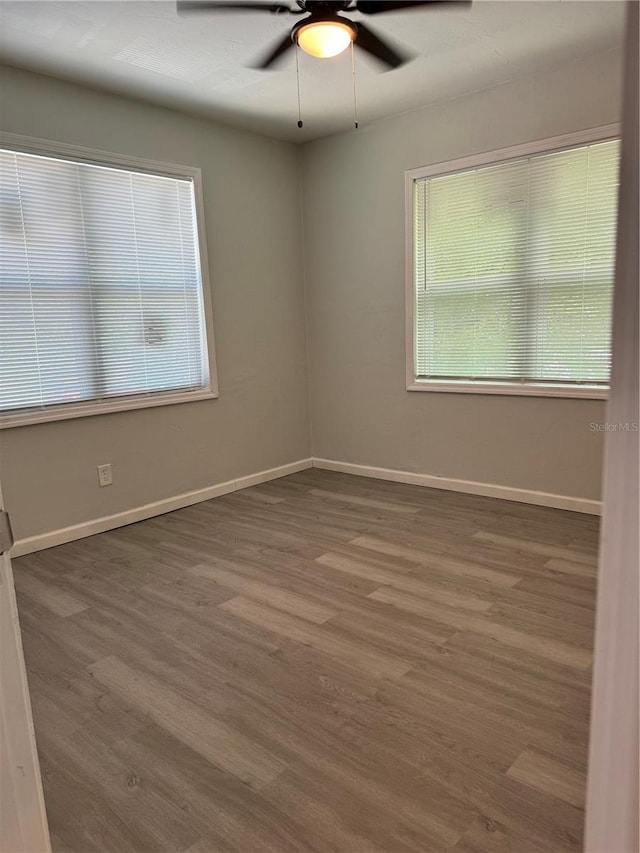 empty room featuring wood finished floors, baseboards, and ceiling fan