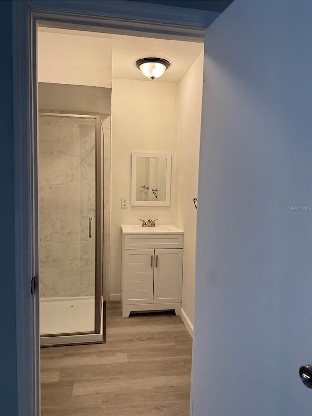 bathroom featuring a shower with shower door, hardwood / wood-style flooring, and vanity