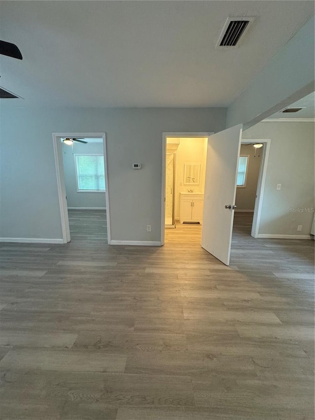 interior space with a ceiling fan, wood finished floors, visible vents, and baseboards