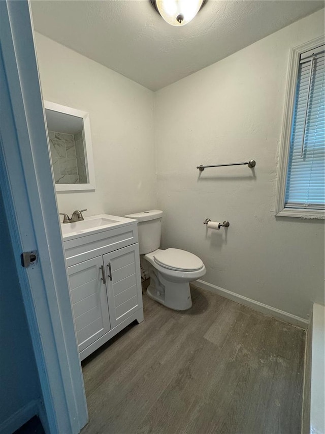 bathroom featuring vanity, toilet, wood finished floors, and baseboards