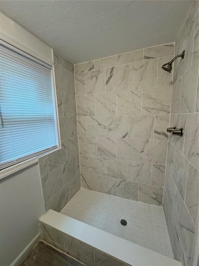 bathroom with tiled shower and a textured ceiling