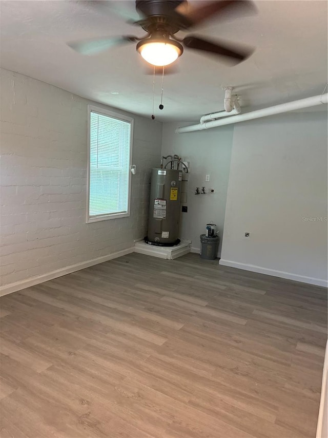 unfurnished living room featuring ceiling fan, brick wall, wood-type flooring, and water heater