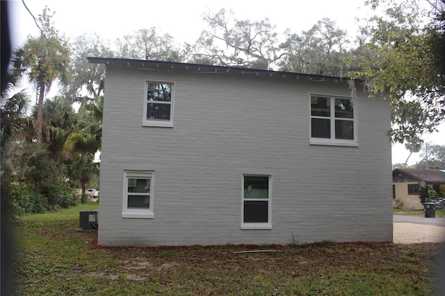 view of property exterior featuring central AC unit and a lawn