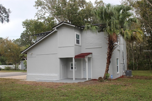 rear view of property featuring a yard and central AC unit