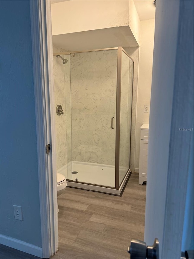 bathroom featuring toilet, hardwood / wood-style flooring, vanity, and a shower with shower door