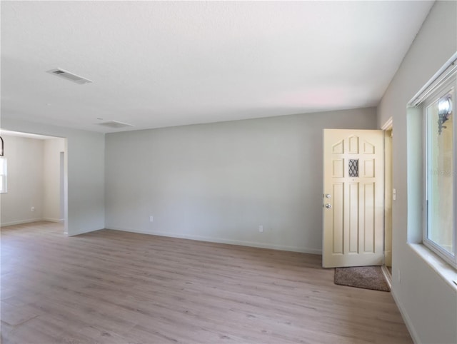 spare room featuring plenty of natural light and light hardwood / wood-style floors