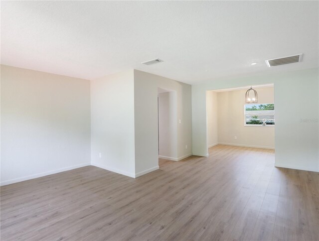 empty room with a chandelier and light hardwood / wood-style flooring