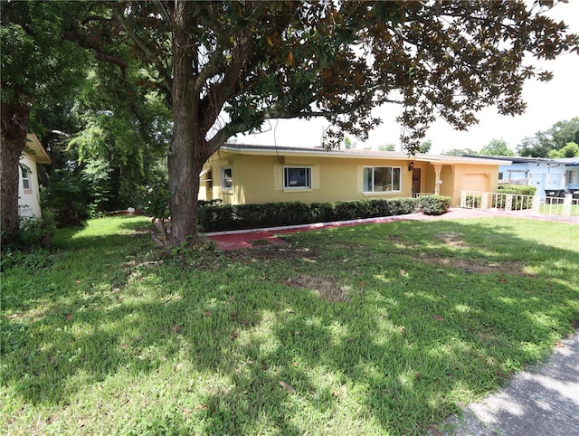 single story home featuring an attached garage, a front lawn, and stucco siding