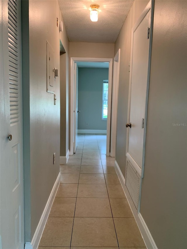 hall featuring electric panel, light tile patterned floors, and a textured ceiling