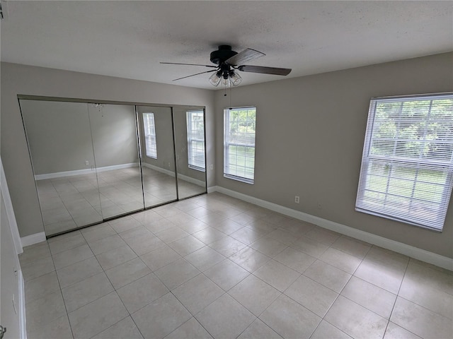 unfurnished bedroom with a closet, light tile patterned floors, and ceiling fan