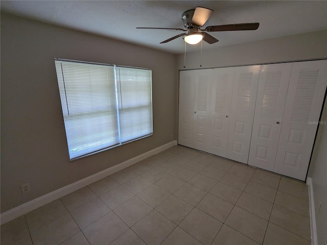 unfurnished bedroom featuring light tile patterned flooring, ceiling fan, and a closet