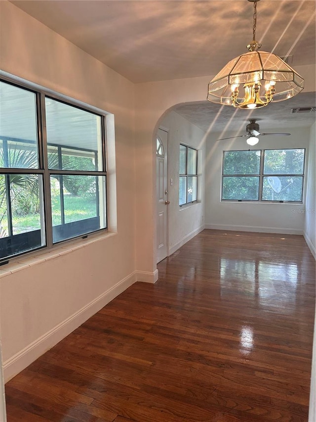 spare room with visible vents, arched walkways, baseboards, and wood finished floors