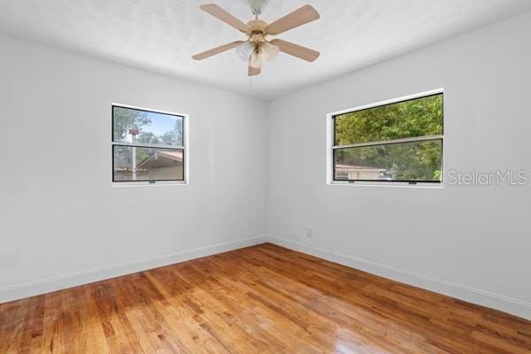 spare room featuring ceiling fan, light wood-type flooring, and baseboards