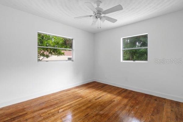 empty room with ceiling fan, baseboards, and wood finished floors