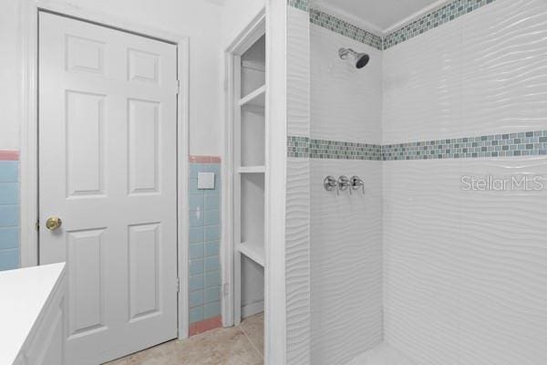 full bath featuring tile patterned floors, tile walls, vanity, and a tile shower