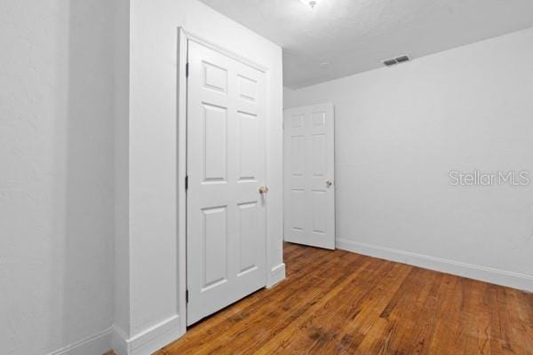 unfurnished room featuring visible vents, baseboards, and wood finished floors