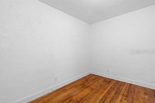 unfurnished room with baseboards and wood finished floors