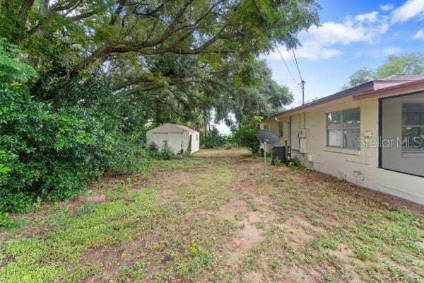 view of yard featuring an outdoor structure, central AC, and a shed