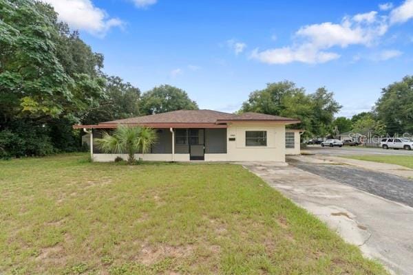 view of front of property with a front yard, driveway, and a sunroom