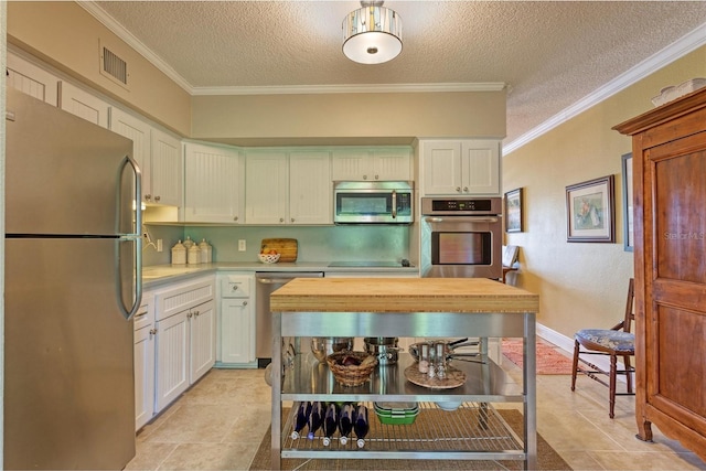 kitchen featuring appliances with stainless steel finishes, light tile patterned floors, a textured ceiling, and crown molding