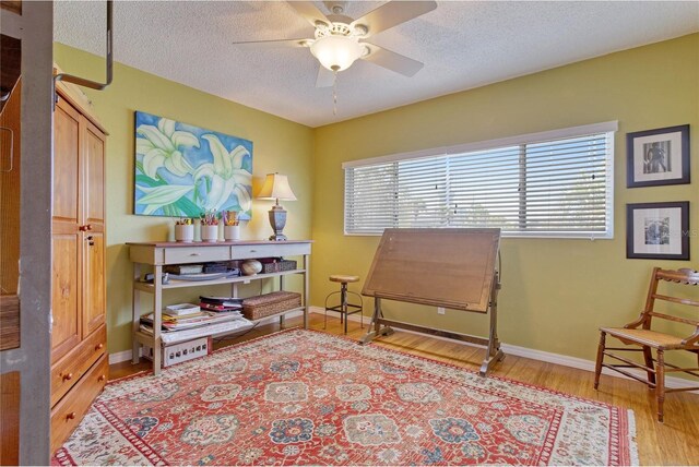 sitting room featuring plenty of natural light, a textured ceiling, ceiling fan, and light hardwood / wood-style floors