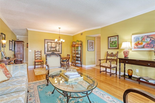 living room featuring light hardwood / wood-style floors, ornamental molding, a chandelier, and a textured ceiling