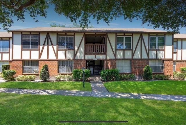 view of front of property with brick siding, stucco siding, and a front lawn