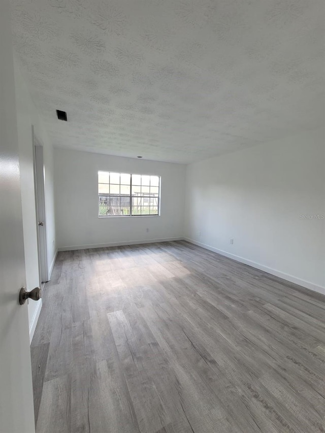 empty room with hardwood / wood-style flooring and a textured ceiling