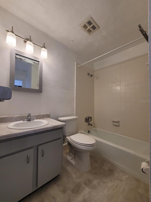 full bathroom with vanity, tiled shower / bath combo, toilet, a textured ceiling, and tile patterned flooring