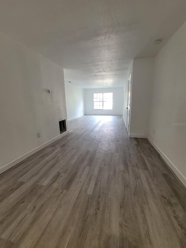 unfurnished living room with a textured ceiling and wood-type flooring