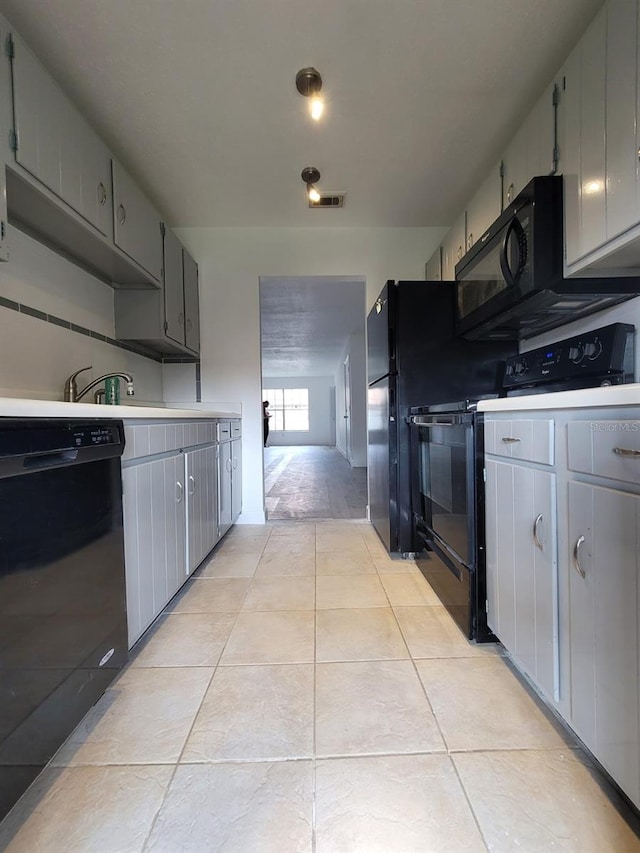 kitchen with gray cabinets, black appliances, and light tile patterned floors