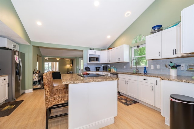 kitchen with appliances with stainless steel finishes, tasteful backsplash, a center island, and a healthy amount of sunlight