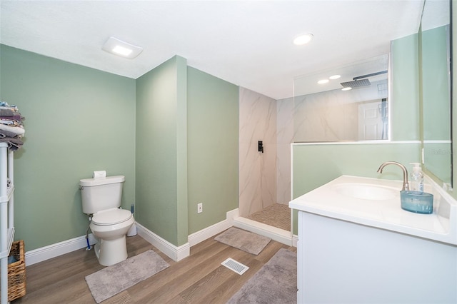 bathroom with vanity, a tile shower, toilet, and hardwood / wood-style floors