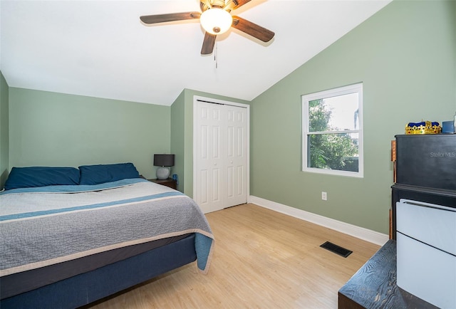 bedroom with ceiling fan, light wood-type flooring, a closet, and vaulted ceiling