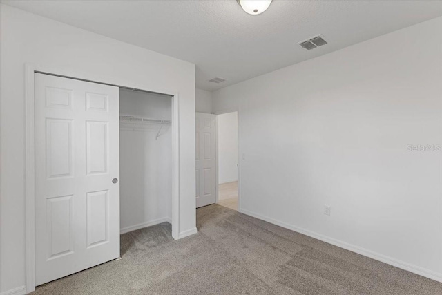 unfurnished bedroom with light carpet and a closet