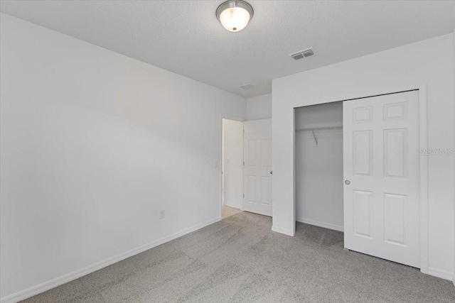 unfurnished bedroom with a closet, light carpet, and a textured ceiling