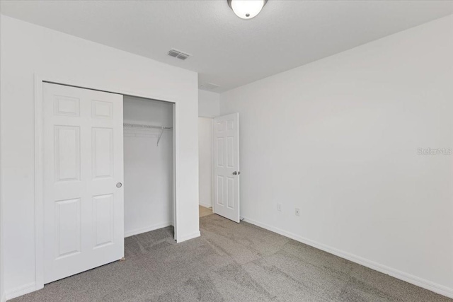 unfurnished bedroom with light colored carpet and a closet