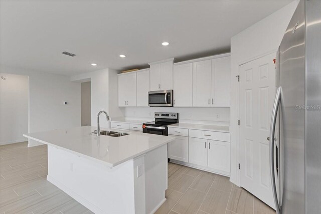 kitchen featuring appliances with stainless steel finishes, sink, a kitchen island with sink, and white cabinets