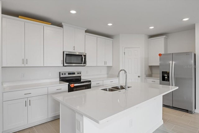 kitchen with white cabinetry, appliances with stainless steel finishes, sink, and a center island with sink