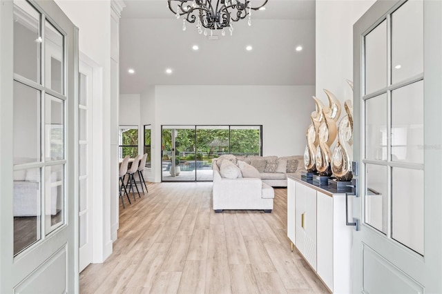 living room with a chandelier, light hardwood / wood-style flooring, and a high ceiling