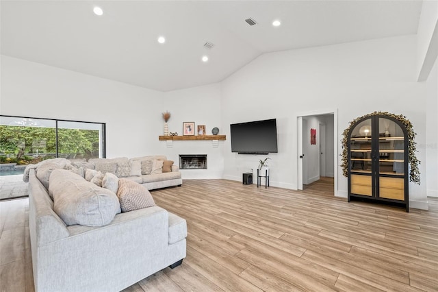 living room with high vaulted ceiling and light hardwood / wood-style floors