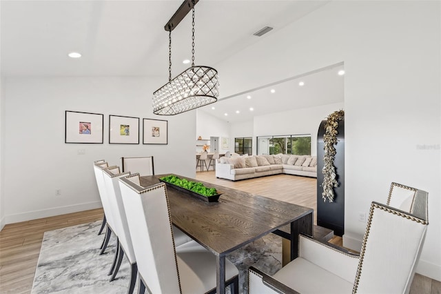 dining room featuring lofted ceiling, a notable chandelier, and light hardwood / wood-style flooring