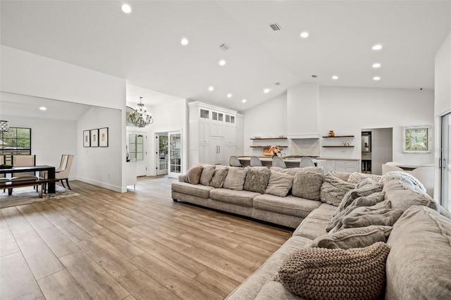 living room featuring a wealth of natural light, a notable chandelier, high vaulted ceiling, and light hardwood / wood-style flooring