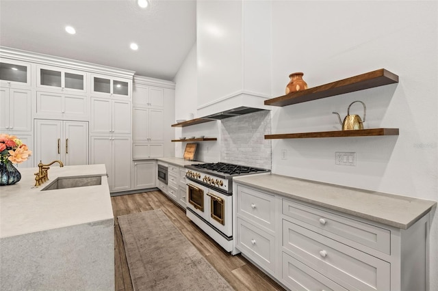 kitchen with sink, white cabinetry, stainless steel microwave, wood-type flooring, and range with two ovens