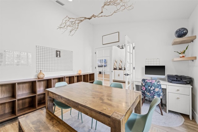 dining room with lofted ceiling, light hardwood / wood-style flooring, and french doors