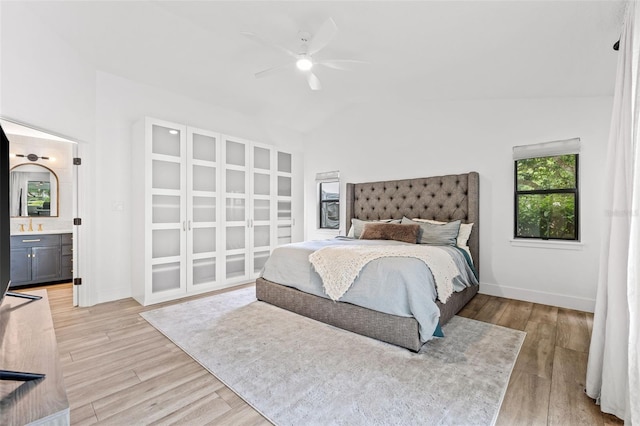 bedroom with connected bathroom, vaulted ceiling, and light wood-type flooring