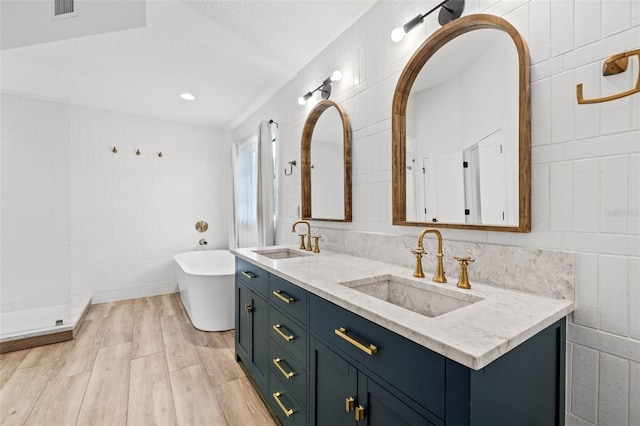 bathroom with hardwood / wood-style flooring, tile walls, vanity, a textured ceiling, and independent shower and bath