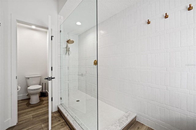 bathroom featuring a tile shower, hardwood / wood-style floors, and toilet